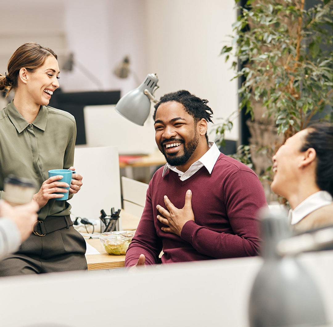 Team of employees smiling and chatting casually in a modern office setting